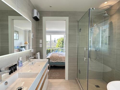 a bathroom with two sinks and a glass shower at Stunning Rothesay Bay in Auckland