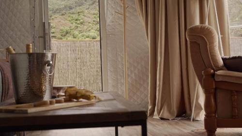 a living room with a table and a chair and a window at The Barn Cabins & Camp in Marahau
