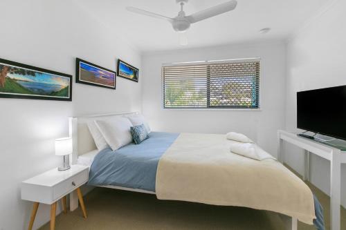 a bedroom with a bed and a flat screen tv at Kings Bay Apartments in Caloundra