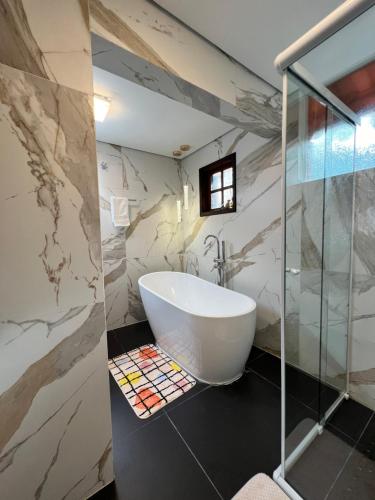 a bathroom with a tub and a glass shower at Vila Husky in Campos do Jordão