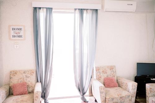 a living room with two chairs and a large window at La Playa Suites 2 in Periyiálion