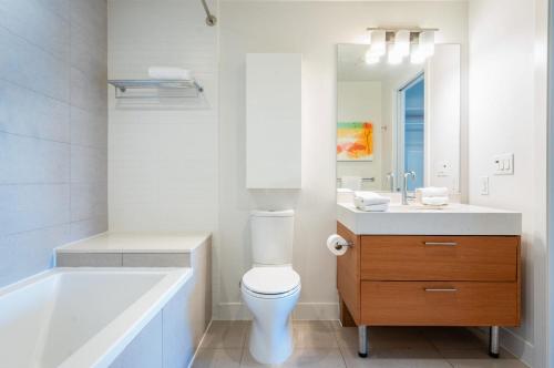 a bathroom with a tub and a toilet and a sink at Level Los Angeles - Downtown South Olive in Los Angeles