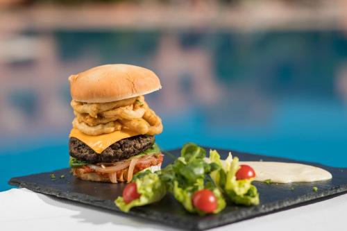 a chicken sandwich on a black plate with a salad at Grand Mogador Agdal & Spa in Marrakech