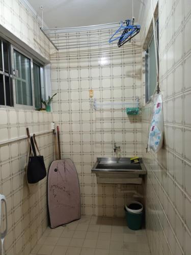 a tiled bathroom with a sink and a mirror at Praia Tombo Guarujá in Guarujá