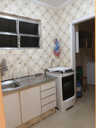 uma cozinha com um lavatório e um fogão forno superior em Praia Tombo Guarujá no Guarujá