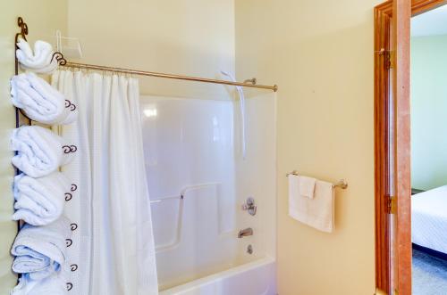 a bathroom with a shower and a tub with towels at Burnside Resort Cabin with Hot Tub and Outdoor Spots! in Burnside