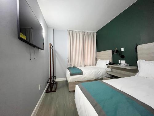 a hotel room with two beds and a television at Starlight Hotel Near LGA Airport in Queens