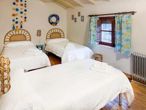 two beds in a room with white sheets at Charming Casa Rural El Pedregal 