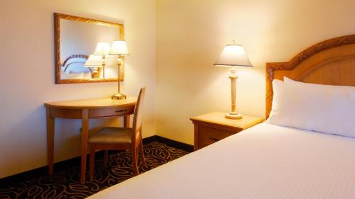 a hotel room with a bed and a desk and a mirror at Eldorado Reno, A Caesars Destination in Reno