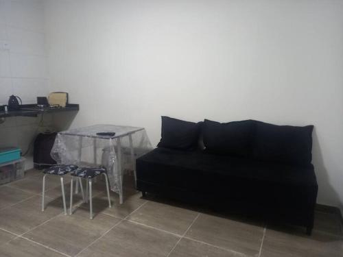 a living room with a black couch and a table at Casa em Unamar, Cabo Frio - com piscina privativa in Cabo Frio