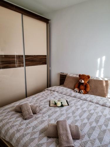 a large bed with a teddy bear and a tray on it at Apartman Nevena in Vrnjačka Banja