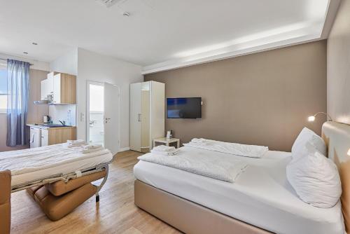 a bedroom with a large white bed and a kitchen at Boardinghotel Heidelberg in Heidelberg