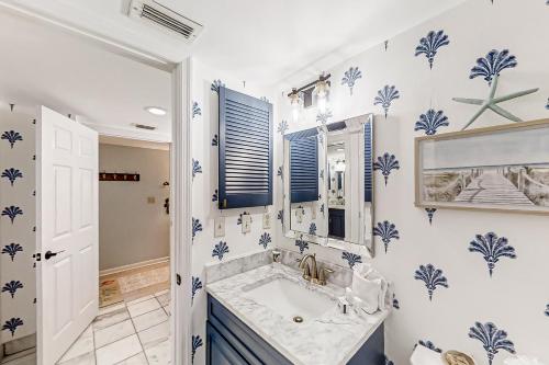 Baño con papel pintado azul y blanco y lavabo en Ocean’s Treasures Retreat Beach Condo, en Ponte Vedra Beach