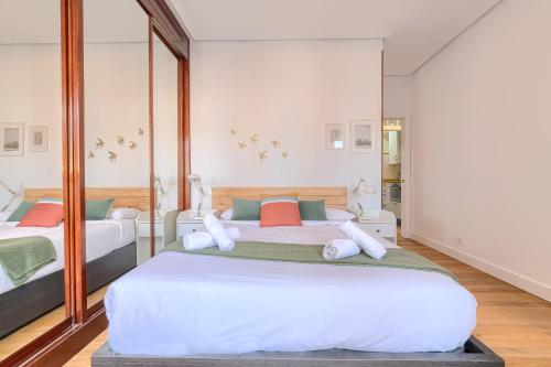 a bedroom with two beds and a mirror at Iturribide Hogar Moderno junto al Metro in Bilbao