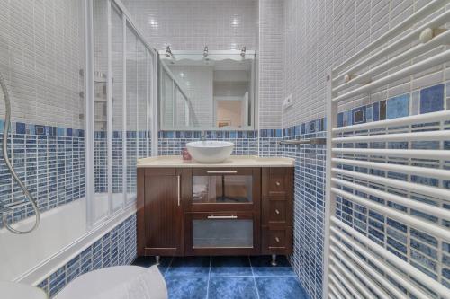 baño con lavabo y paredes de azulejos azules en Iturribide Hogar Moderno junto al Metro en Bilbao