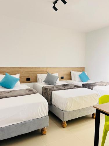 a room with three beds with blue pillows at HOTEL 9.5 SAN FERNANDO in Cali