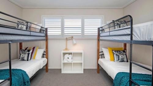 two bunk beds in a room with a window at Alpine Snow Angels Retreat in Jindabyne