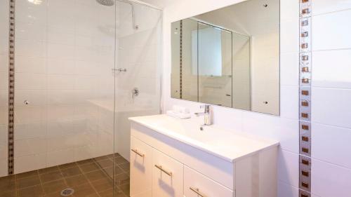 a white bathroom with a sink and a shower at Alpine Snow Angels Retreat in Jindabyne