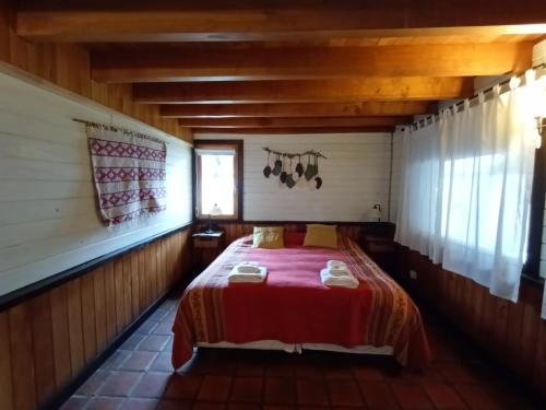 1 dormitorio con 1 cama en una casa de madera en Alojamiento Los Huillines en San Martín de los Andes