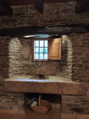 Baño de piedra con lavabo y ventana en Casa Moucheiro, en Lugo