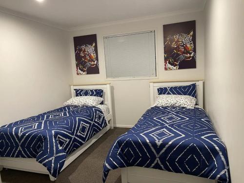 a bedroom with two beds with blue and white comforters at An elegant 2-bedroom house in Hamilton central. in Hamilton