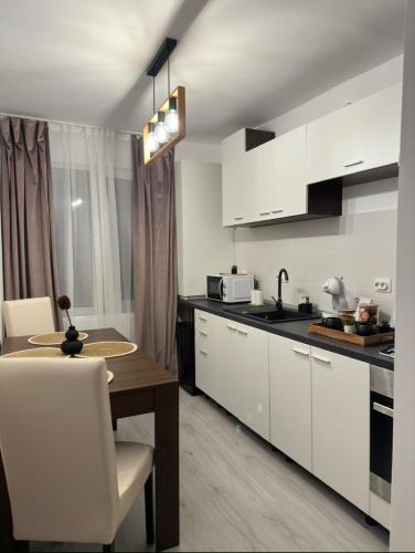 a kitchen with white cabinets and a wooden table at Saguna Residence2 in Sighişoara