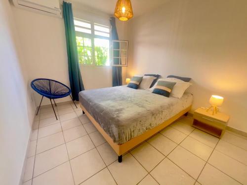 a bedroom with a bed and a chair and a window at Villa Iguana, duplex paisible, vue magnifique mer et rocher du Diamant, piscine in Sainte-Luce