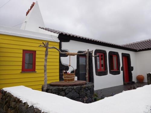 a yellow and white house with a basket in front of it at Casa do Poço in Santa Bárbara