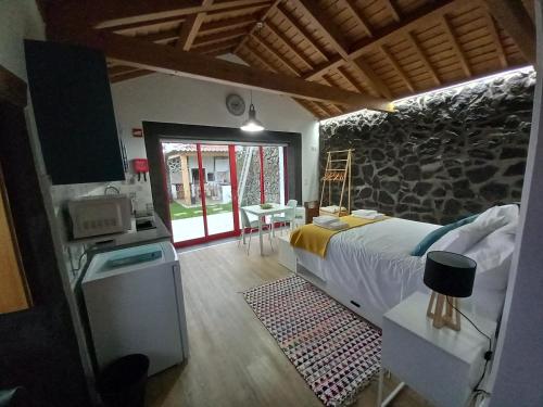 a bedroom with a large bed and a stone wall at Casa do Poço in Santa Bárbara
