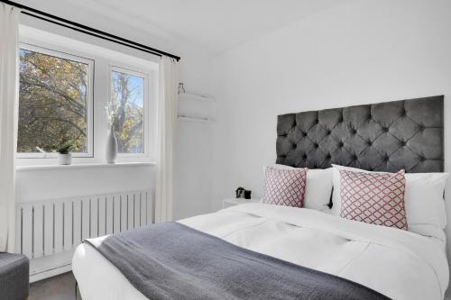 a white bedroom with a bed and a window at Peckham apartments by APS in London