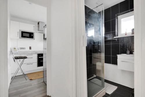 a bathroom with a shower with black tiles at Peckham apartments by APS in London