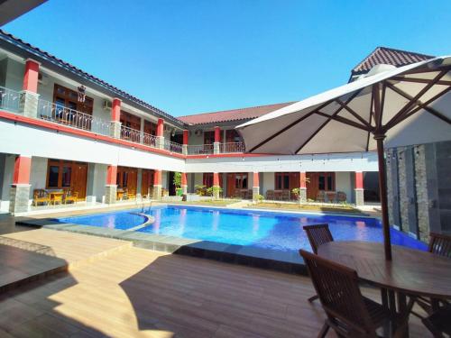 a swimming pool with a table and an umbrella at Hotel Asri Baru in Purwokerto
