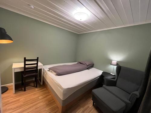 1 dormitorio con cama, silla y escritorio en Koselig rom i rolige omgivelser, en Åmot