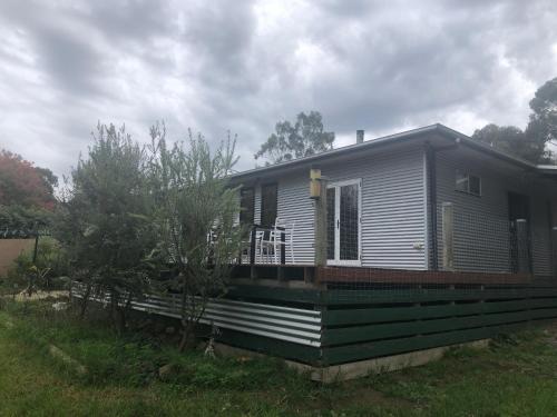 a small house with a porch on a field at Peaks Trail Rest Dunkeld in Dunkeld