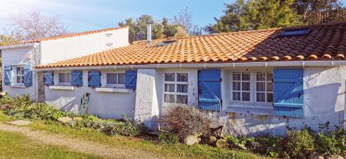 uma casa branca com janelas azuis e um telhado vermelho em La Maison du pêcheur - Jacuzzi em Jard-sur-Mer