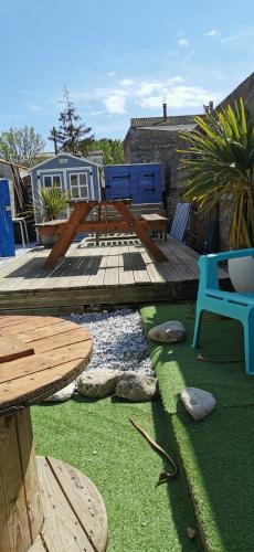 a patio with a picnic table and benches and grass at La Maison du pêcheur - Jacuzzi 3 Etoiles in Jard-sur-Mer