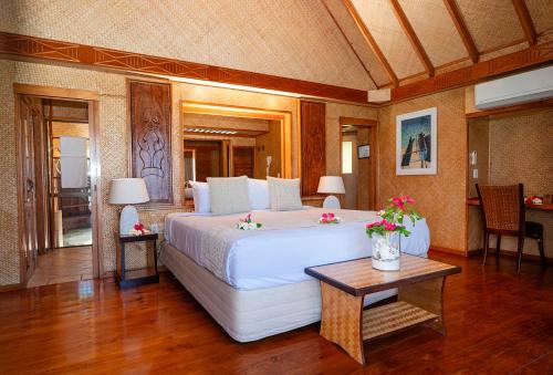 um quarto com uma grande cama branca e uma mesa em Aitutaki Lagoon Private Island Resort (Adults Only) em Arutanga