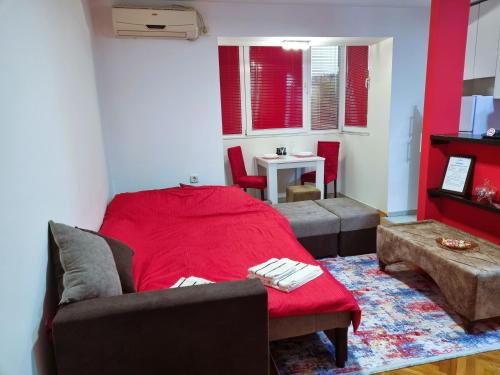 uma sala de estar com uma cama vermelha e um sofá em A&P Apartments em Skopje