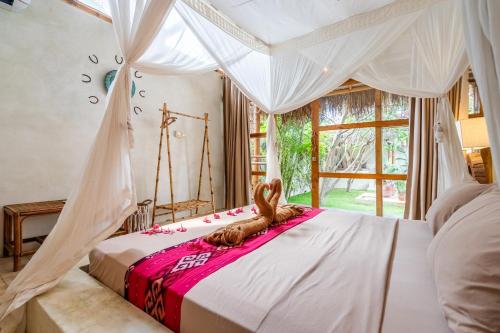 ein Schlafzimmer mit einem Himmelbett mit einem Kaninchen darauf in der Unterkunft Villa Burung Gili Air in Gili Air