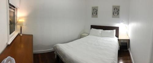 a bedroom with a white bed and a wooden floor at Low price clean linen and free stuff No 2 plenty of on street parking G1 in Sydney