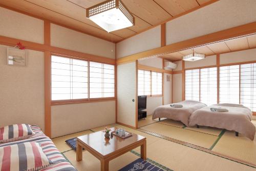 een woonkamer met 2 bedden en een tafel bij Guesthouse Ichigo Ichie Nikko in Nikko