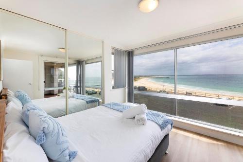 two beds in a bedroom with a view of the beach at El Sandi Unit 06 in Forster
