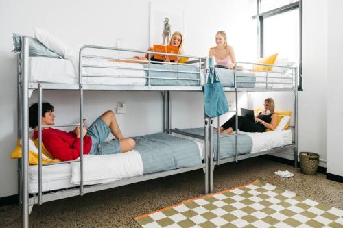 grupa osób siedzących na łóżkach piętrowych w obiekcie The Village Hostels Canberra w mieście Canberra