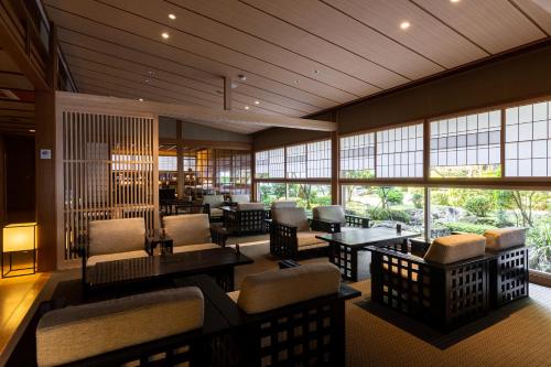 un vestíbulo con sillas, mesas y ventanas en Tokiwa Bekkan en Toyooka