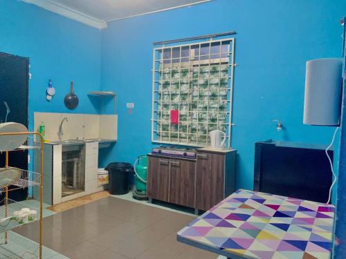 a kitchen with blue walls and a table in a room at D'NARS HOMESTAY KEMAMAN in Cukai