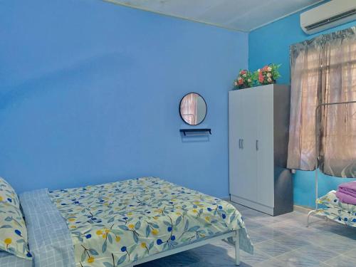 a bedroom with a blue wall with a bed in it at D'NARS HOMESTAY KEMAMAN in Cukai