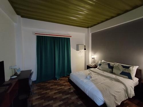 a bedroom with a bed and a green curtain at RedDoorz @ LQJ Hotel Old Buswang Kalibo in Kalibo