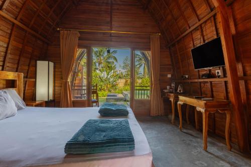 een slaapkamer met een bed, een televisie en een bureau bij Kubu Selat Villa and Glamping in Gianyar