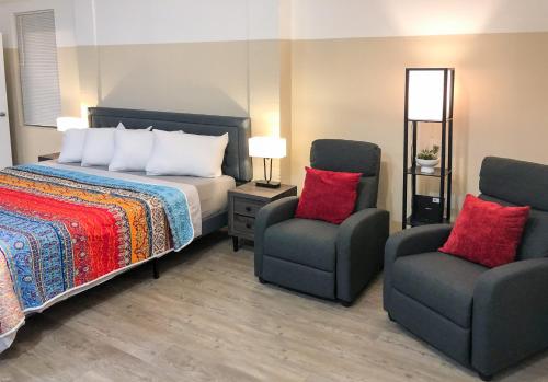 a bedroom with a bed and two chairs at Star Apartments in Fort Myers