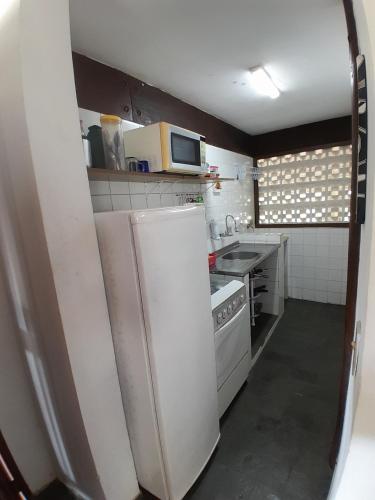 a small kitchen with a refrigerator and a microwave at Chalés Recanto da Praia in Caraguatatuba